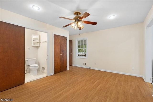 unfurnished bedroom featuring light wood-style flooring, baseboards, ensuite bath, and ceiling fan