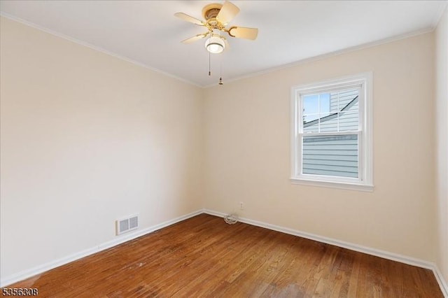 empty room with baseboards, wood finished floors, crown molding, and a ceiling fan