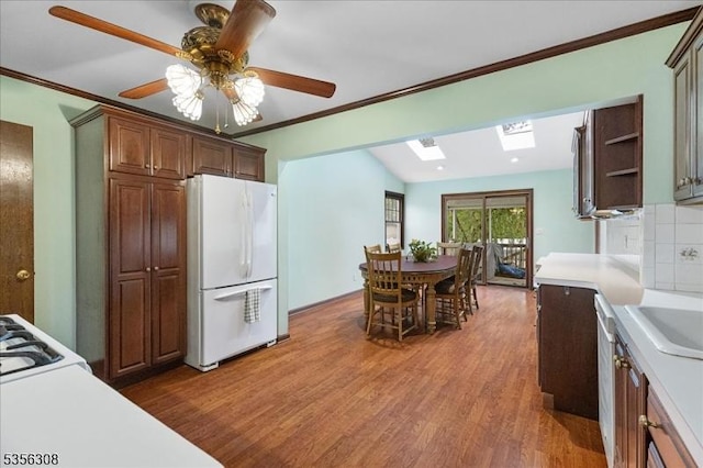 kitchen with freestanding refrigerator, light countertops, a skylight, wood finished floors, and crown molding