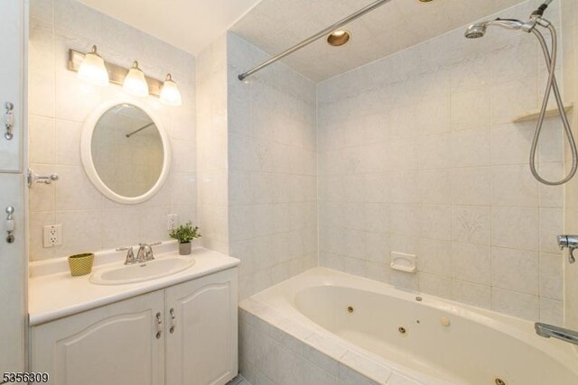 full bath featuring tile walls, vanity, and a combined bath / shower with jetted tub