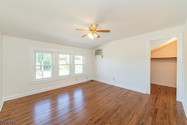 unfurnished bedroom featuring wood finished floors, baseboards, a spacious closet, a ceiling fan, and lofted ceiling