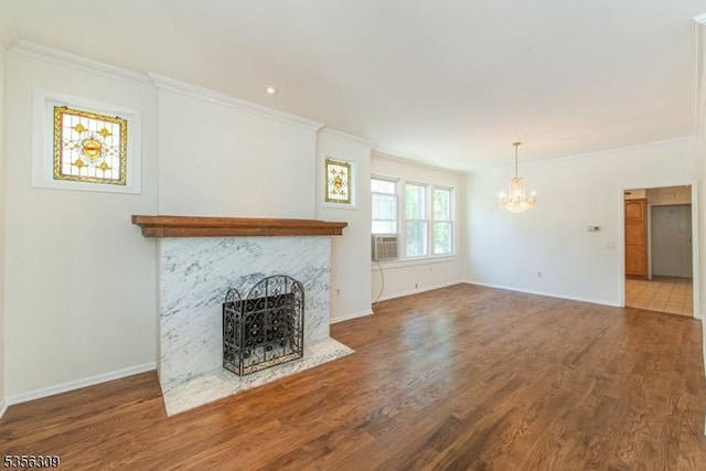 unfurnished living room featuring a chandelier, crown molding, wood finished floors, a high end fireplace, and baseboards
