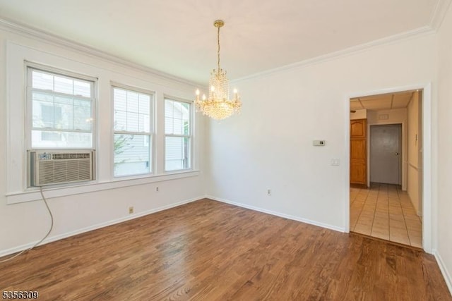 empty room with a chandelier, wood finished floors, cooling unit, crown molding, and baseboards