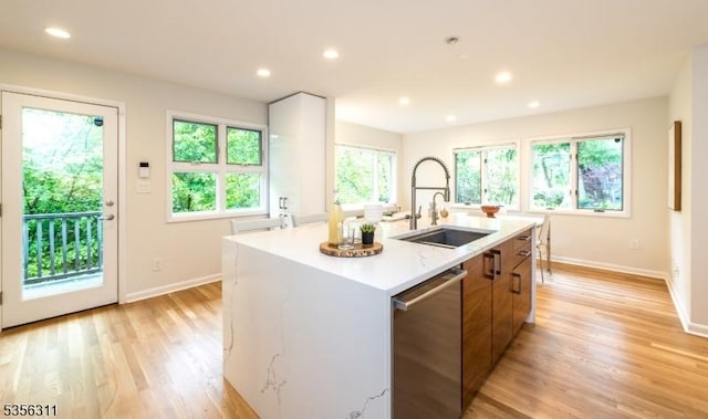 kitchen with a sink, dishwasher, baseboards, light countertops, and recessed lighting