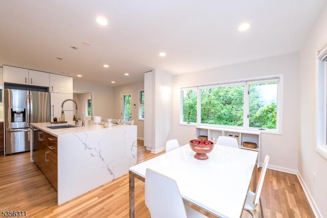 kitchen featuring appliances with stainless steel finishes, a sink, modern cabinets, white cabinetry, and light wood-style floors