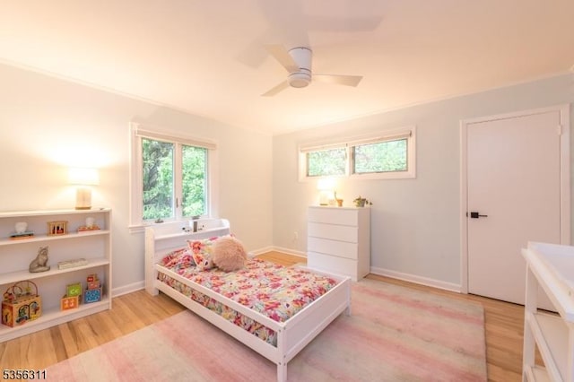 bedroom featuring light wood-style floors, a ceiling fan, and baseboards
