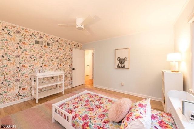 bedroom with wood finished floors, baseboards, wallpapered walls, and ceiling fan
