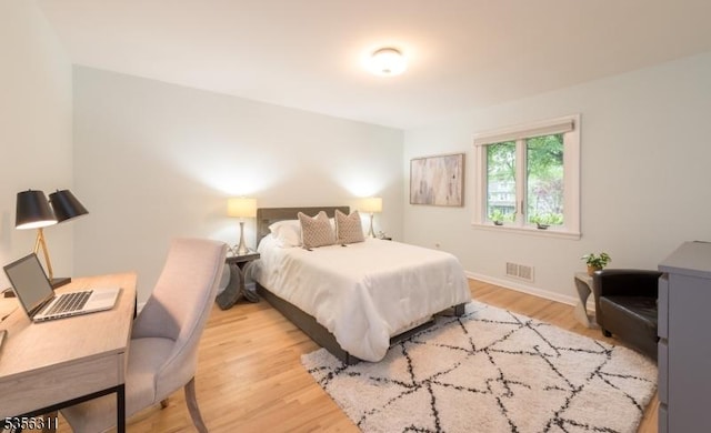 bedroom with wood finished floors, baseboards, and an office area