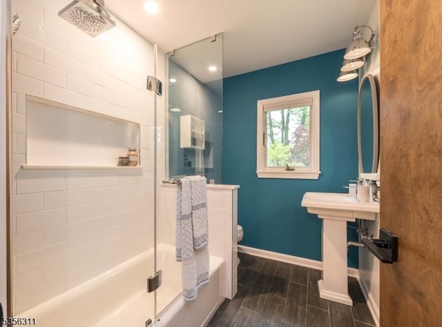 bathroom featuring wood finished floors, toilet, bath / shower combo with glass door, baseboards, and recessed lighting