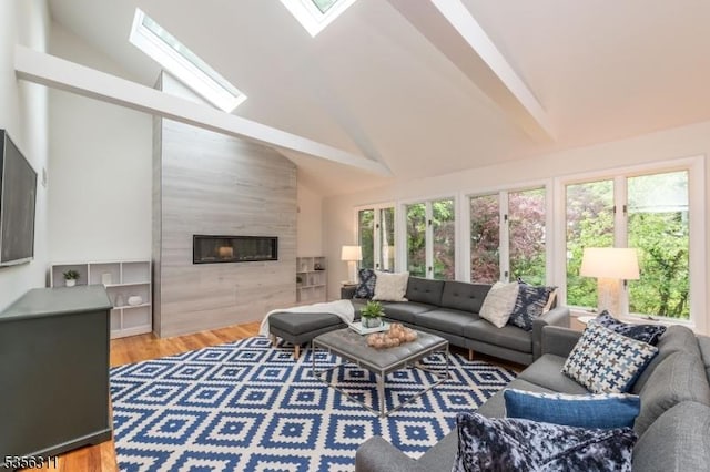 living room with high vaulted ceiling, a fireplace, a skylight, beam ceiling, and wood finished floors