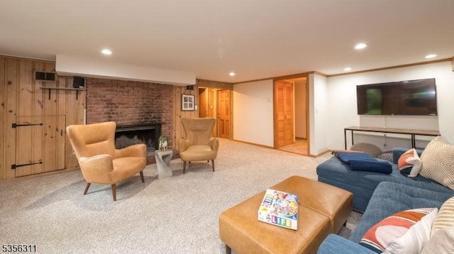 living room with carpet floors, recessed lighting, a brick fireplace, and wood walls