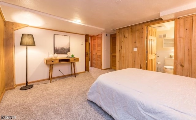 bedroom with carpet, connected bathroom, baseboards, and wood walls