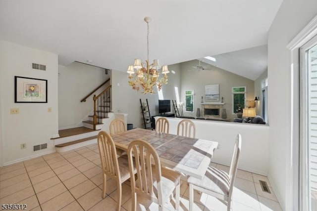 dining room featuring light tile patterned floors, vaulted ceiling, a chandelier, stairs, and plenty of natural light