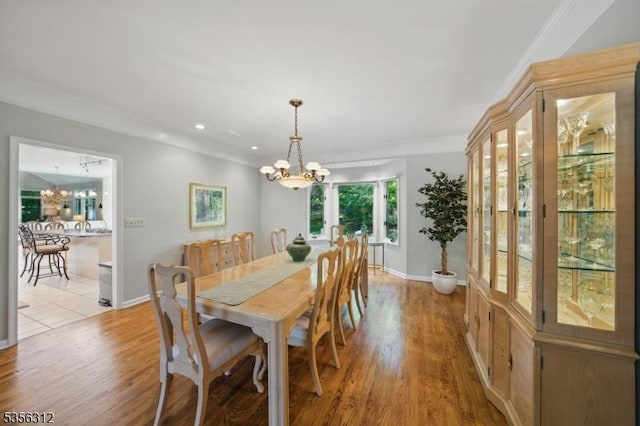 dining room featuring a chandelier, light wood finished floors, crown molding, baseboards, and recessed lighting