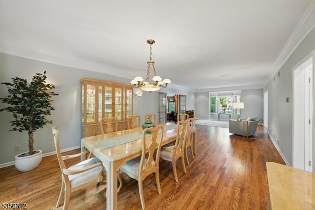 dining room with a chandelier, wood finished floors, crown molding, and baseboards