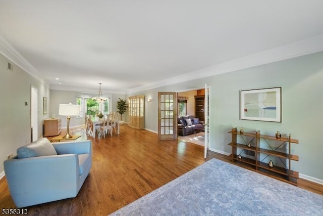 living area featuring wood finished floors, crown molding, baseboards, a chandelier, and french doors