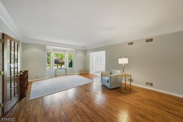 sitting room featuring wood finished floors, baseboards, crown molding, and french doors