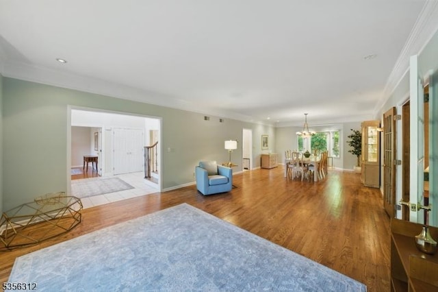 living room with wood finished floors, crown molding, a chandelier, and baseboards