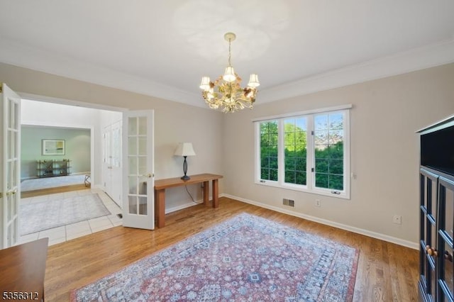 dining space with french doors, a chandelier, wood finished floors, crown molding, and baseboards