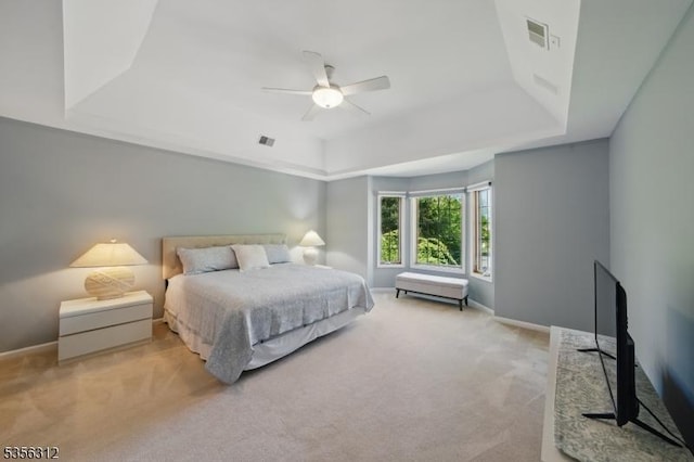 bedroom featuring a tray ceiling, light carpet, baseboards, and a ceiling fan