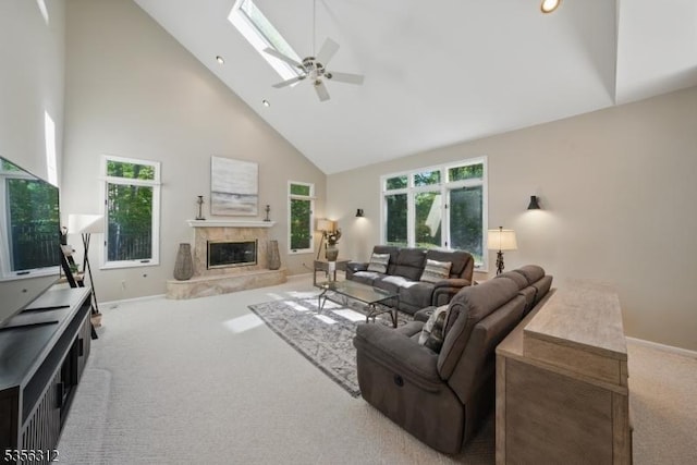 living area with high vaulted ceiling, carpet, a skylight, ceiling fan, and baseboards