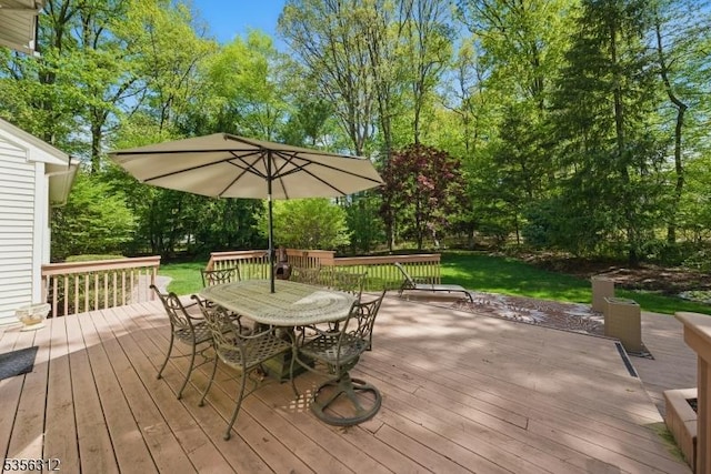 wooden terrace featuring outdoor dining space and view of wooded area