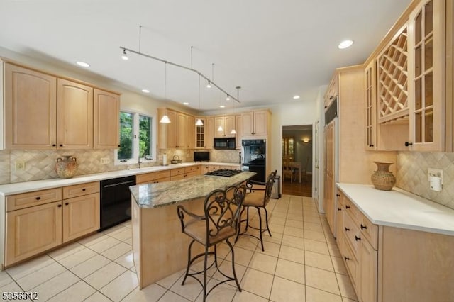 kitchen featuring black appliances, light brown cabinetry, a breakfast bar area, decorative backsplash, and light tile patterned floors