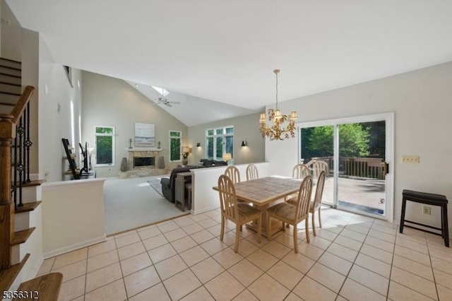 dining room with a chandelier, a glass covered fireplace, light tile patterned floors, and lofted ceiling