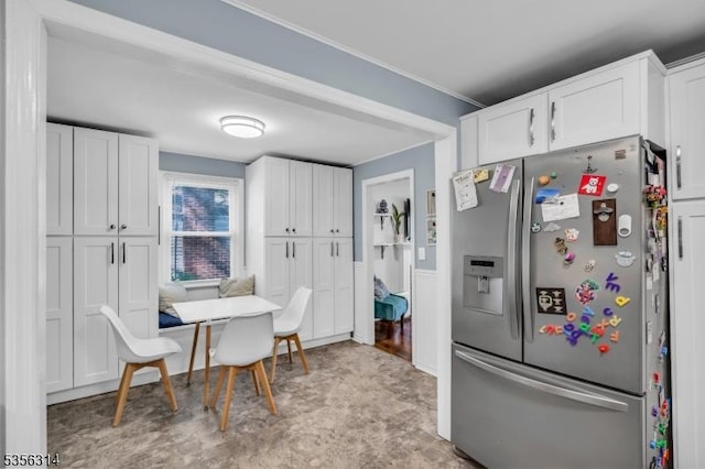 kitchen with stainless steel fridge, white cabinets, and ornamental molding