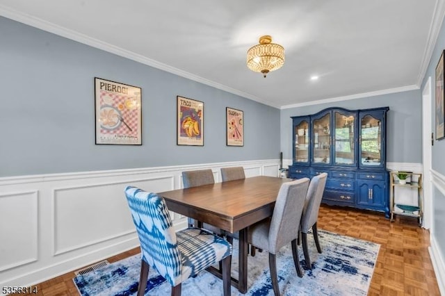 dining area featuring crown molding, a chandelier, and wainscoting
