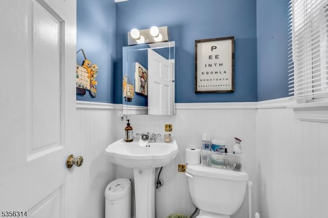 half bathroom with a wainscoted wall and toilet