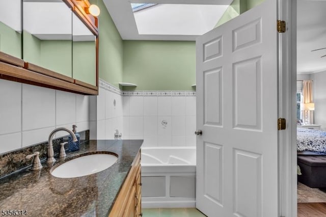 full bath featuring a skylight, a bath, vanity, ensuite bath, and decorative backsplash