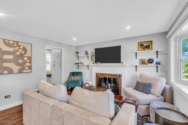 living room with baseboards, wood finished floors, a brick fireplace, and recessed lighting