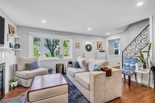 living area featuring healthy amount of natural light, a glass covered fireplace, recessed lighting, and wood finished floors