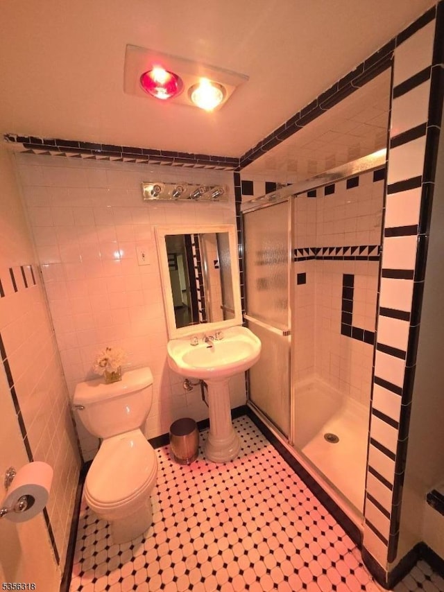 full bath with a stall shower, toilet, and tile walls