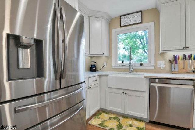 kitchen with stainless steel appliances, white cabinetry, and a sink