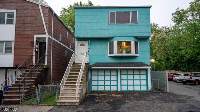view of front of property with stairway, fence, a garage, asphalt driveway, and a gate