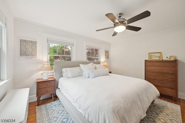 bedroom featuring wood finished floors, baseboards, ceiling fan, and ornamental molding