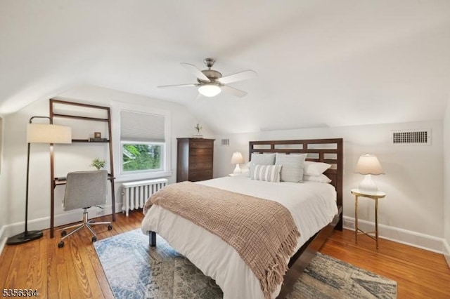 bedroom featuring radiator, baseboards, lofted ceiling, wood finished floors, and ceiling fan