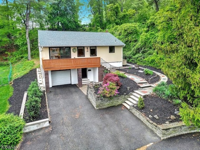 view of front of property featuring stairway, an attached garage, asphalt driveway, and a shingled roof