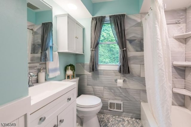 bathroom featuring tile walls, toilet, shower / tub combo with curtain, vanity, and tile patterned flooring