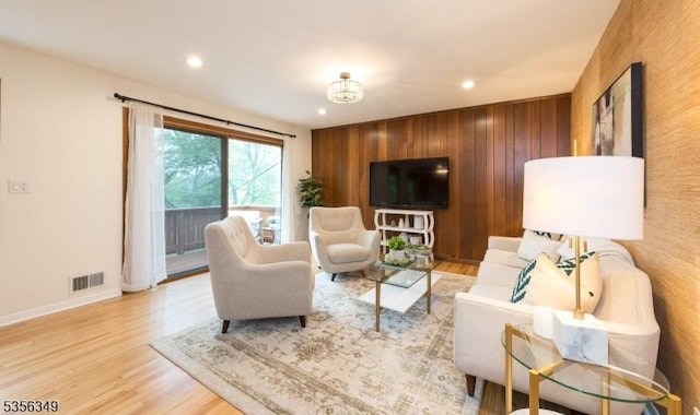 living room with baseboards, recessed lighting, light wood-style floors, and wooden walls