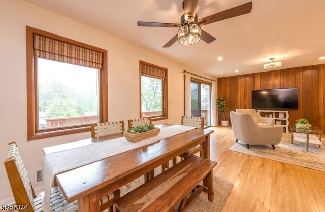 dining area featuring recessed lighting, light wood-style floors, a ceiling fan, and wooden walls