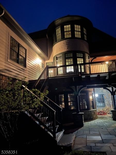 152 Whitebridge Rd, Franklin Twp, NJ 08867 - back of house at night featuring stone siding, a patio area, a balcony, and stairs