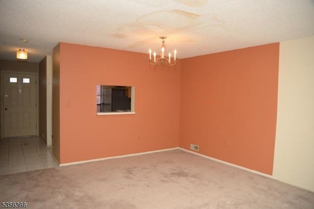 carpeted empty room featuring a chandelier and baseboards