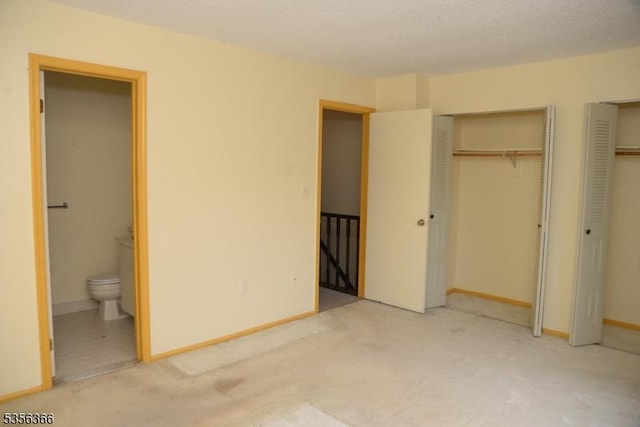 unfurnished bedroom featuring two closets, ensuite bath, light carpet, and baseboards