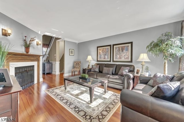 living area with crown molding, wood finished floors, a fireplace, and baseboards