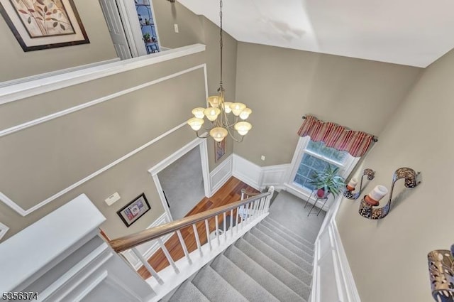 stairway featuring a chandelier and a wainscoted wall