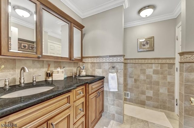 full bath featuring double vanity, tile walls, crown molding, wainscoting, and tile patterned floors