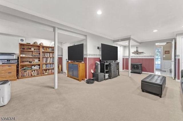living room featuring a wainscoted wall, carpet flooring, crown molding, recessed lighting, and a wood stove